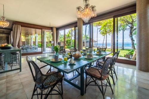 a dining room with a table and chairs with a view of the ocean at Villa Manis Beachfront Candidasa in Candidasa