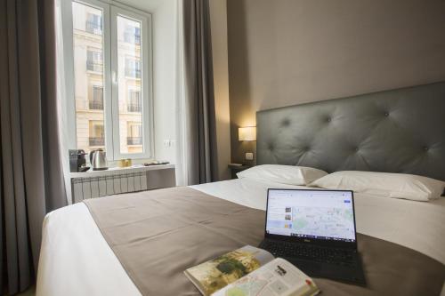 un ordenador portátil sentado en una cama en una habitación de hotel en Colosseo Prestige Rooms, en Roma