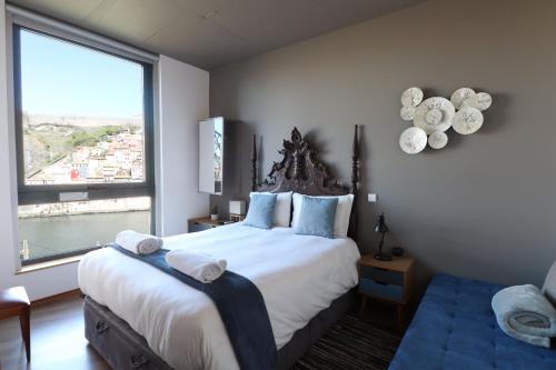 a bedroom with a large bed with a large window at Bridge It - Suites & Views in Vila Nova de Gaia