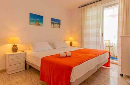 sypialnia z łóżkiem z pomarańczowym kocem w obiekcie 797 HOLIDAY RENTALS - Piso para 4 con amplia terraza al jardin y al mar w mieście Benalmádena