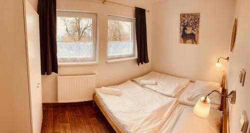 a small bed in a room with two windows at Chalupa Zdíkov na Šumavě in Zdíkov