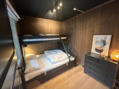 a bedroom with bunk beds in a wooden wall at Slåttastølen - ny og flott sentral leilighet! in Geilo