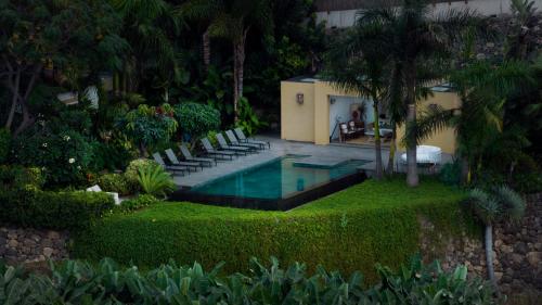 einen Pool in einem Garten mit Stühlen und einem Haus in der Unterkunft Hacienda Cuatro Ventanas in Los Realejos
