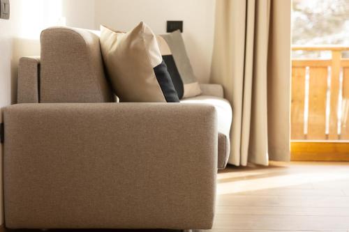 a chair sitting in a living room next to a window at BAITA NOEMI in Livigno