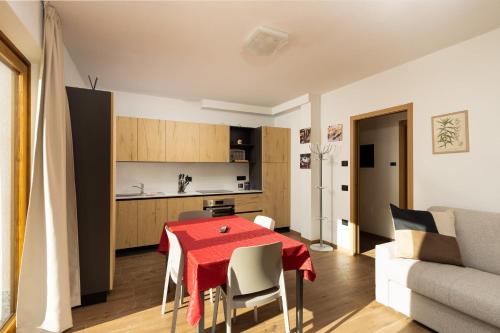 a kitchen and living room with a red table and chairs at BAITA NOEMI in Livigno