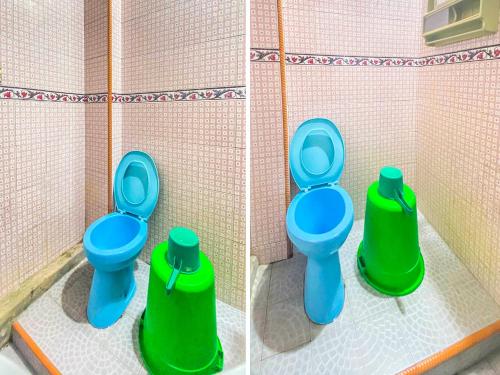 a toy bathroom with two toilets and two green containers at OYO 2518 Wilma Hotel Ii Premier in Kupang
