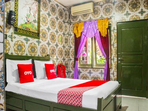 um quarto com uma cama com almofadas vermelhas e uma janela em OYO 2518 Wilma Hotel Ii Premier em Kupang