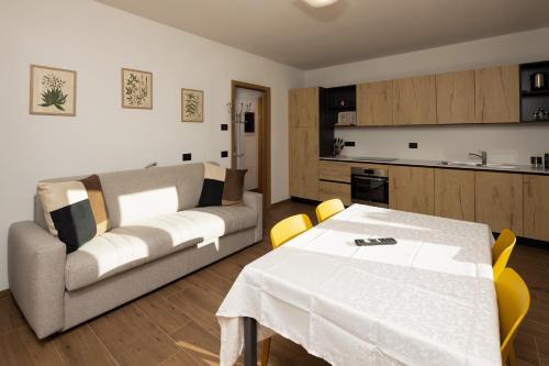 a living room with a couch and a table with yellow chairs at BAITA NOEMI in Livigno
