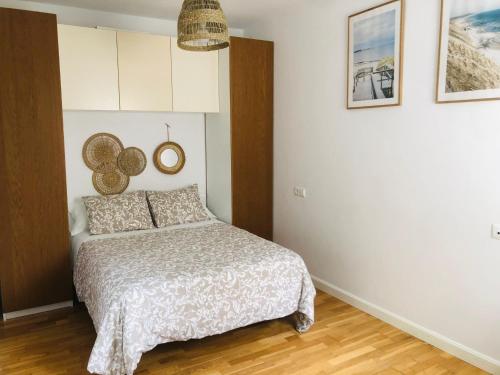 - une chambre avec un lit et deux photos sur le mur dans l'établissement Apartamentos Bahía, à El Puerto de Santa María