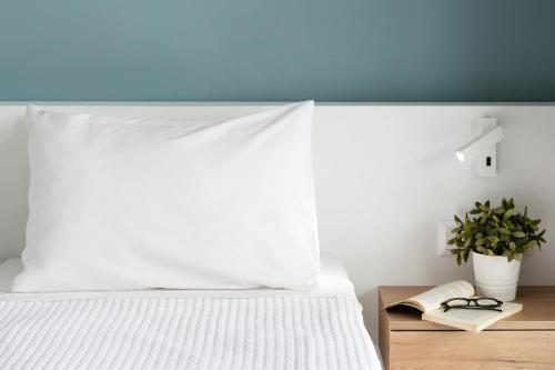a bed with a white pillow and a plant on a table at Olympios Zeus in Plaka Litochorou