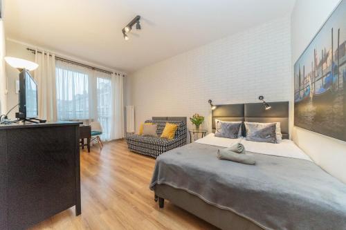 a bedroom with a bed and a desk and a television at Apartamenty Przytulne z balkonem, 150m od dworca Gdańsk Główny in Gdańsk