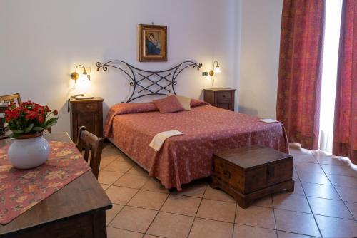 a bedroom with a bed and a table with a vase of flowers at Hotel Villa Sonia in Taormina