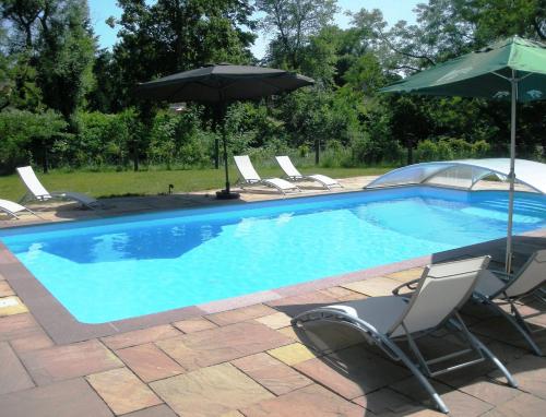 a swimming pool with chairs and umbrellas next to it at Aux Berges de la Thur in Staffelfelden