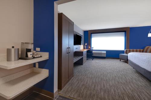 a hotel room with a bed and a desk and a television at Holiday Inn Express & Suites - Grand Rapids South - Wyoming by IHG in Wyoming