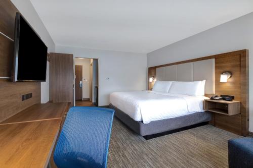 a hotel room with a bed and a flat screen tv at Holiday Inn Express & Suites - Grand Rapids South - Wyoming by IHG in Wyoming