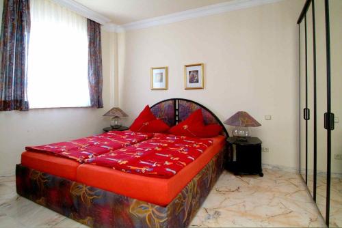 uma cama grande com almofadas vermelhas num quarto em Penthouse Vistamar em Chayofa