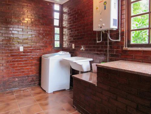 baño con lavabo blanco y pared de ladrillo en Casa de campo Petunia com Wi-Fi e lazer - RJ, en Teresópolis