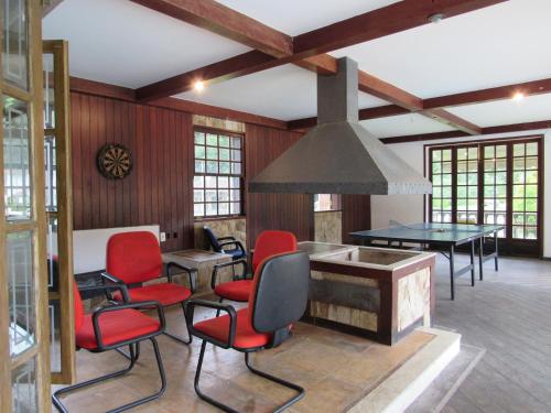 sala de estar con sillas rojas y mesa en Casa de campo Petunia com Wi-Fi e lazer - RJ, en Teresópolis