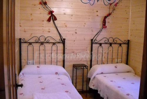 two twin beds in a room with a wooden wall at Apartamento EL Paso in Fuentelisendo