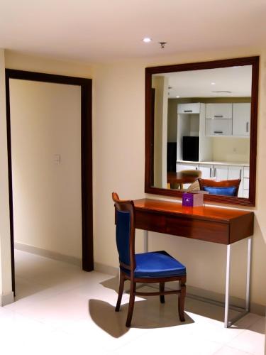 a desk with a mirror and a blue chair at Indigo Heights Hotel & Suites in Lahore