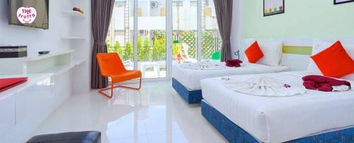 una habitación de hotel con 2 camas y una silla en The Frutta Boutique, en Patong Beach