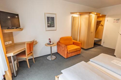 Zimmer mit einem Stuhl, einem Tisch und einem Schreibtisch in der Unterkunft Hotel-Gasthof zum Ritter in Haßmersheim