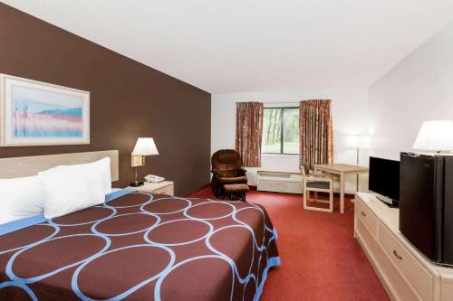 a hotel room with a bed and a flat screen tv at Super 8 by Wyndham Estherville in Estherville