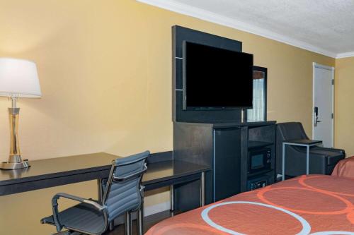 a hotel room with a bed and a desk with a television at Super 8 by Wyndham Ukiah in Ukiah