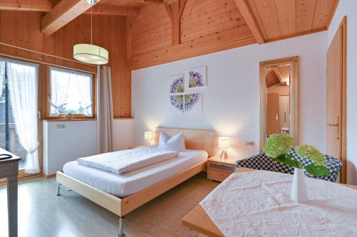 a bedroom with a bed and a table and windows at Landhaus Grobert in Seeg