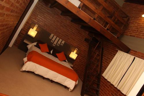 um quarto com uma cama numa parede de tijolos em Apart Hotel TY Coed em Puerto Madryn