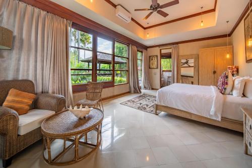 a bedroom with a bed and a couch and a table at Villa Manis Beachfront Candidasa in Candidasa