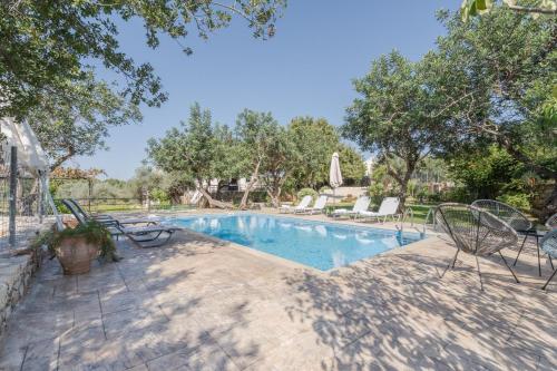 a swimming pool in a yard with chairs and trees at Villa Archodia - With Private Pool in Prinés