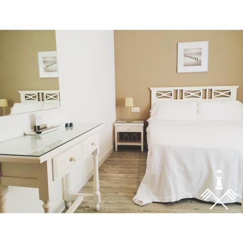 a bedroom with a white bed with a desk and a mirror at Hotel Carbonell in Llança