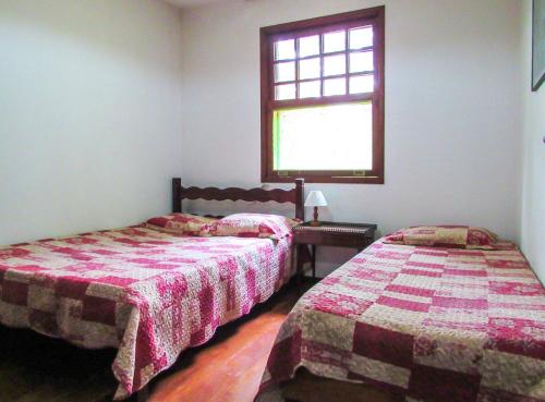 2 camas en una habitación con ventana en Casa de campo Azaleia c churrasqueira e lazer - RJ, en Teresópolis