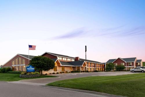 a row of houses in a parking lot with an american flag at AmericInn by Wyndham Sauk Centre in Sauk Centre
