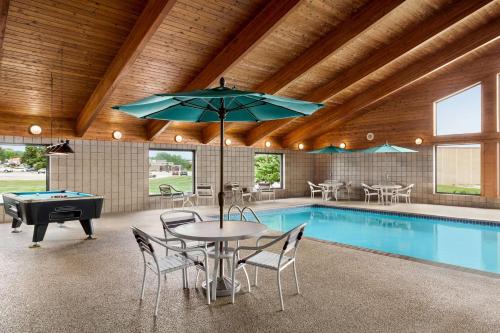 a swimming pool with a table and an umbrella and a pool table at AmericInn by Wyndham Sauk Centre in Sauk Centre