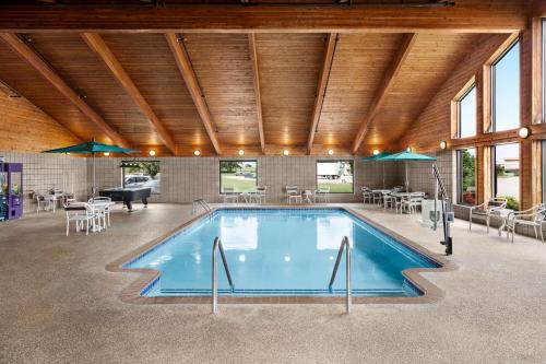a swimming pool with tables and chairs and a piano at AmericInn by Wyndham Sauk Centre in Sauk Centre