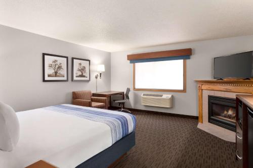 a hotel room with a bed and a fireplace at AmericInn by Wyndham Sauk Centre in Sauk Centre