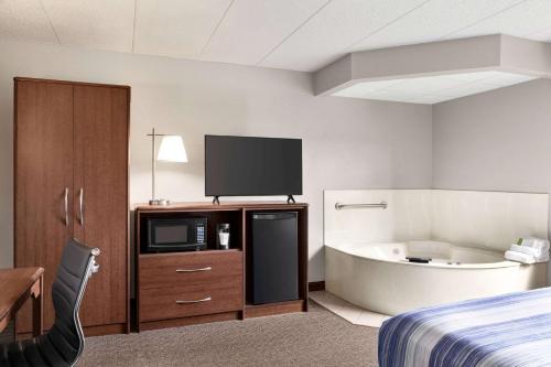 a hotel room with a bed and a tub and a television at AmericInn by Wyndham Sauk Centre in Sauk Centre