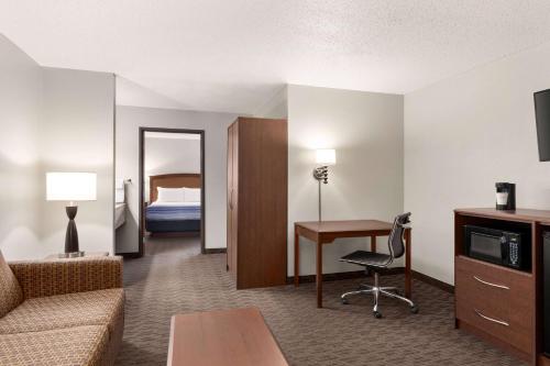 a hotel room with a couch and a desk and a bed at AmericInn by Wyndham Sauk Centre in Sauk Centre