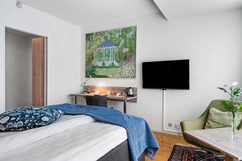a bedroom with a bed and a desk and a tv at Best Western Hotel Varnamo in Värnamo