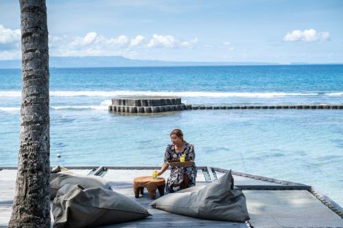 a woman sitting on a table next to the ocean at Villa Manis Beachfront Candidasa in Candidasa