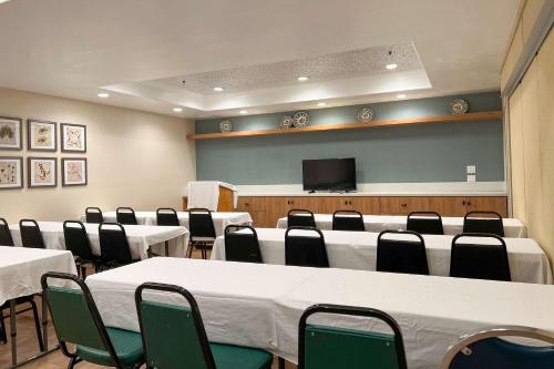 a conference room with tables and chairs and a tv at MainStay Suites John Wayne Airport, a Choice Hotel in Santa Ana