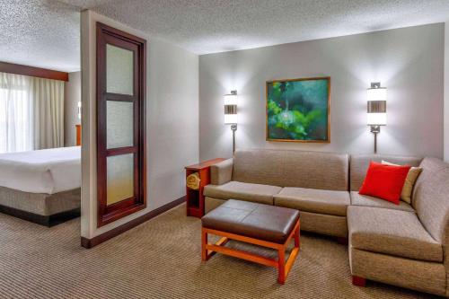 a hotel room with a couch and a bed at Wyndham Garden Kansas City Airport in Kansas City