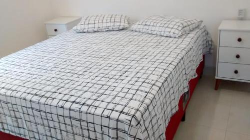 a bedroom with a bed with a checkered blanket and two night stands at Acomodação corporativa: casa residencial recém-construída in Itatiba