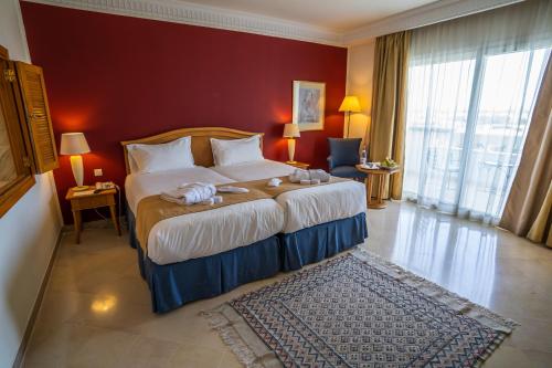 a bedroom with a large bed with a red wall at Vincci Saphir Palace & Spa in Hammamet