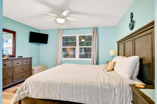 a bedroom with a bed with a ceiling fan and a window at Clipper Cabana Beachwalk Condo in Saint Augustine