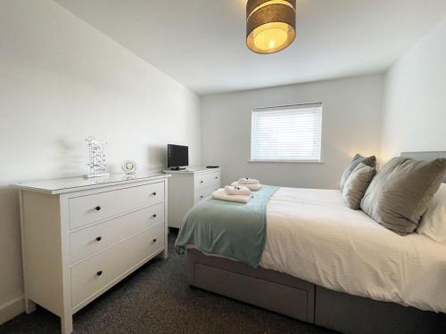 ein Schlafzimmer mit einem weißen Bett und einer Kommode in der Unterkunft 33 Ocean one in Newquay