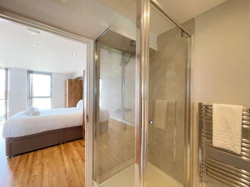 a bathroom with a glass shower and a bed at 38 Zinc in Newquay