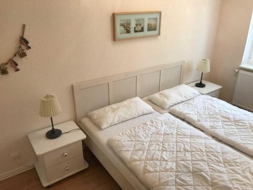 een slaapkamer met een wit bed en 2 nachtkastjes bij MEI4b Ferienwohnung Landkrebs in Niendorf